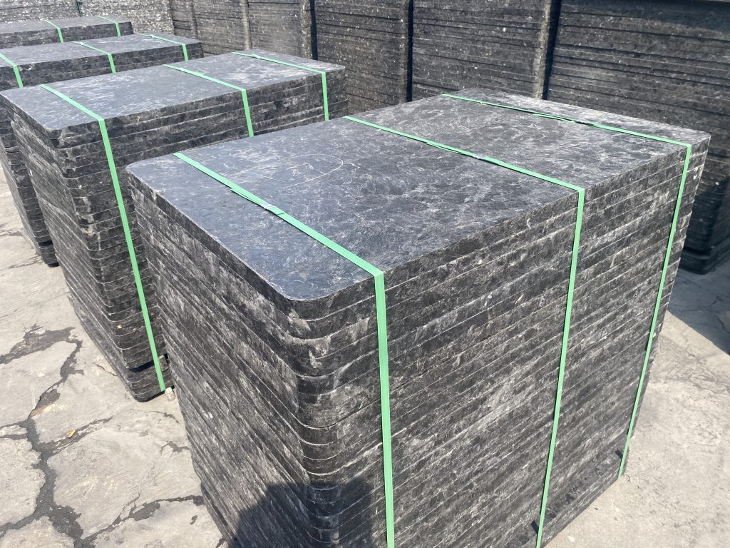 Black glass fiber GMT pallets in direct sunlight showing heat absorption during brick curing process